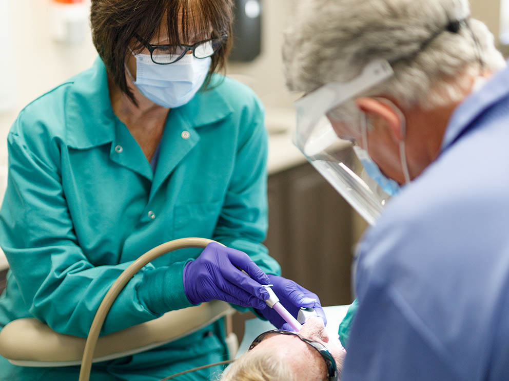 Nurse and dentist assisting patient.